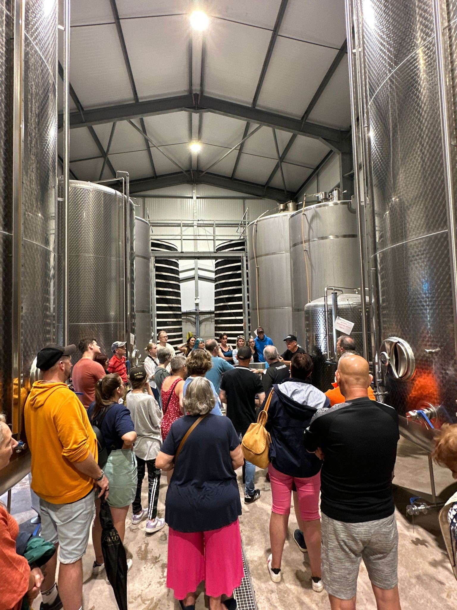A tour group gathered among the steel vats in the vat house