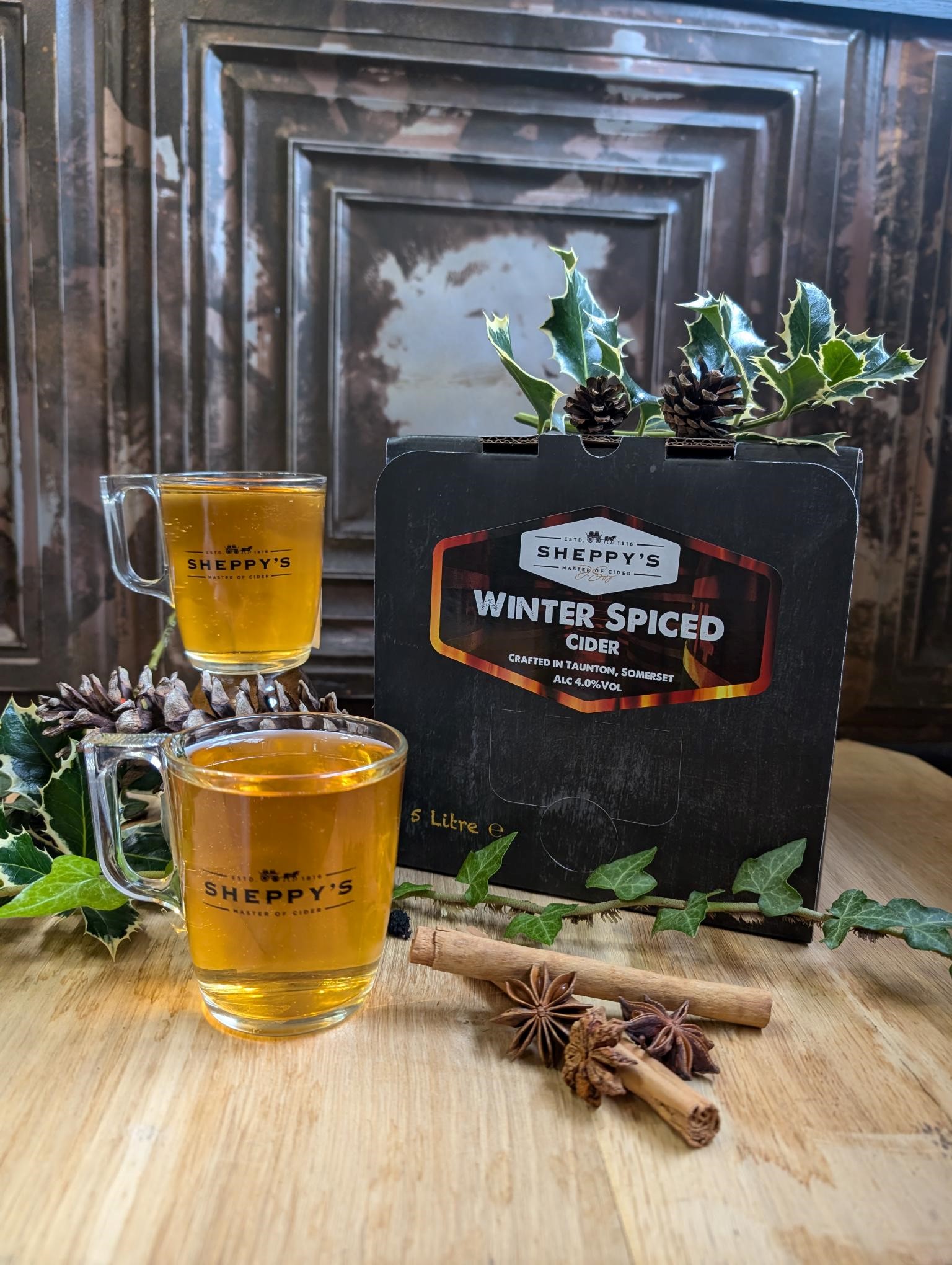 Winter Spiced cider in glass mugs beside its bag-in-box